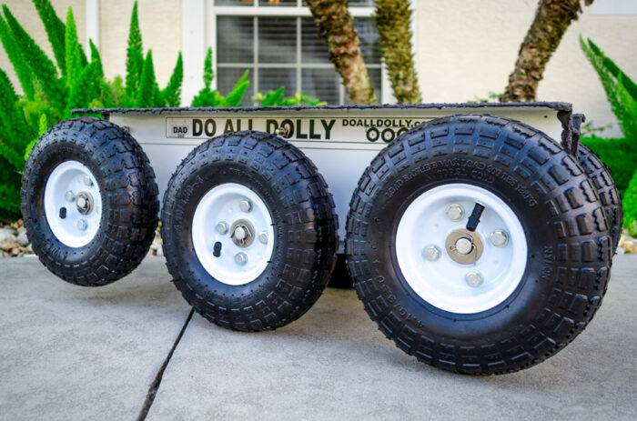 Three tires are on a dolly that is parked.